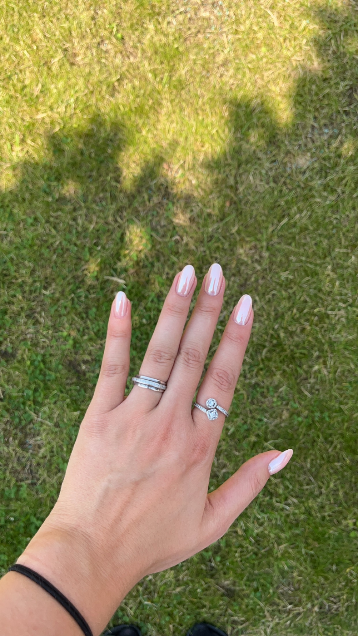 Lichtroze amandelnagels en ringen, hand op het gras