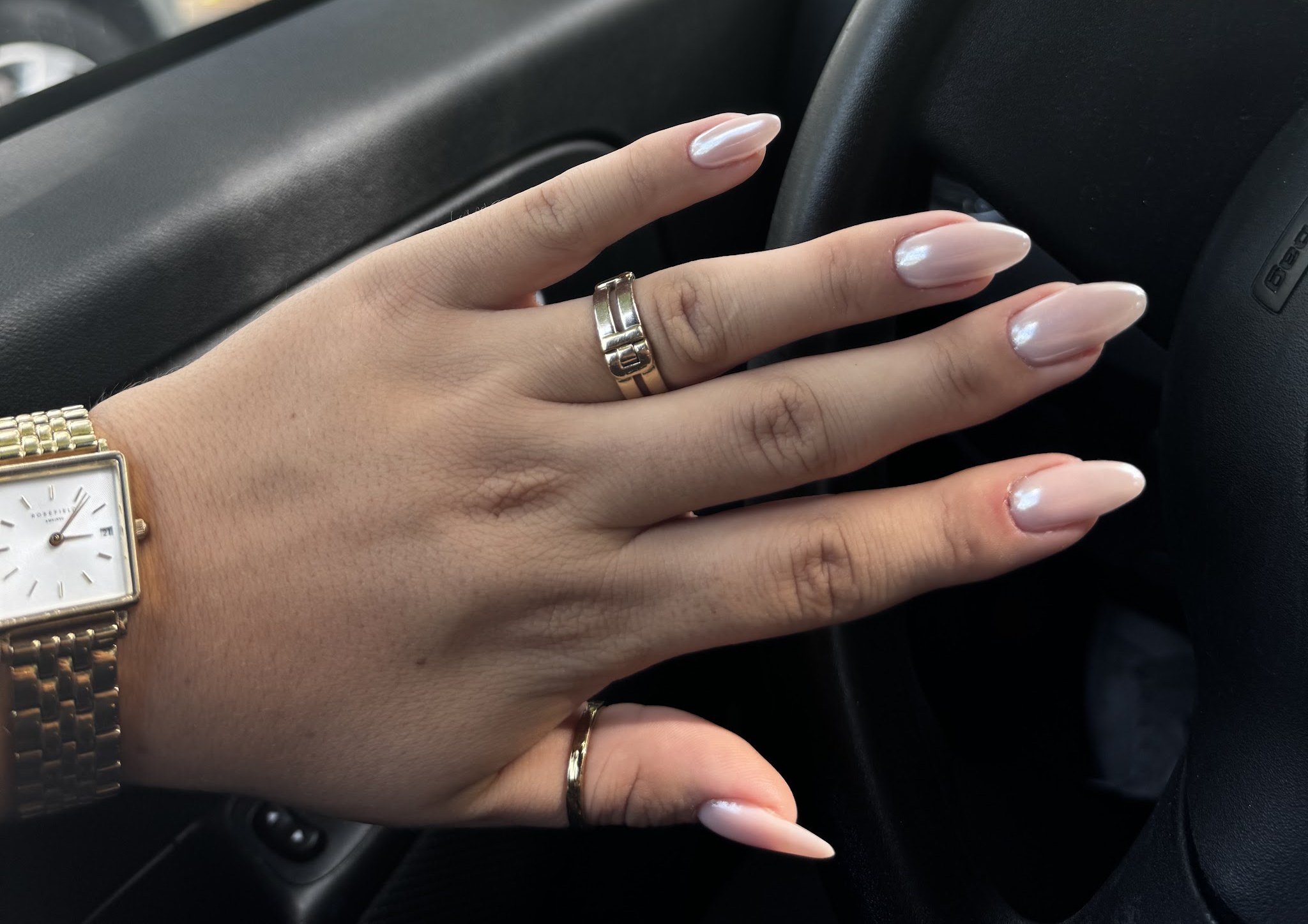 Parelmoer amandelnagels, een hand met horloge en ringen