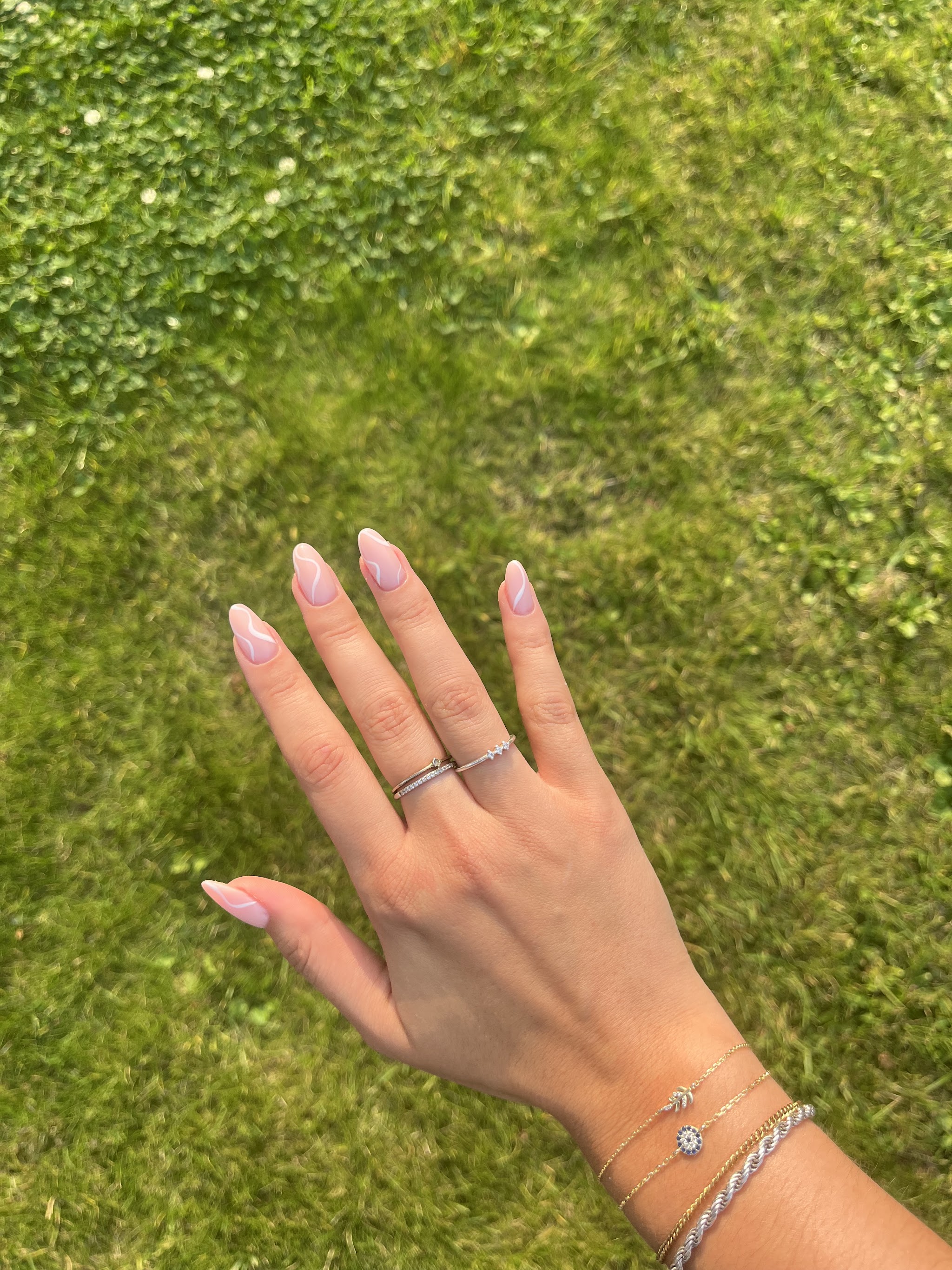 Amandelvormige nagels en armbandjes, hand op het gras